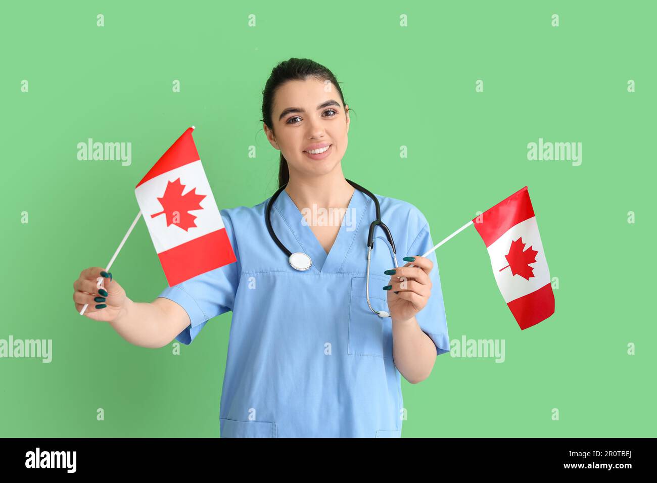 Médico femenino con banderas de Canadá sobre fondo verde Foto de stock