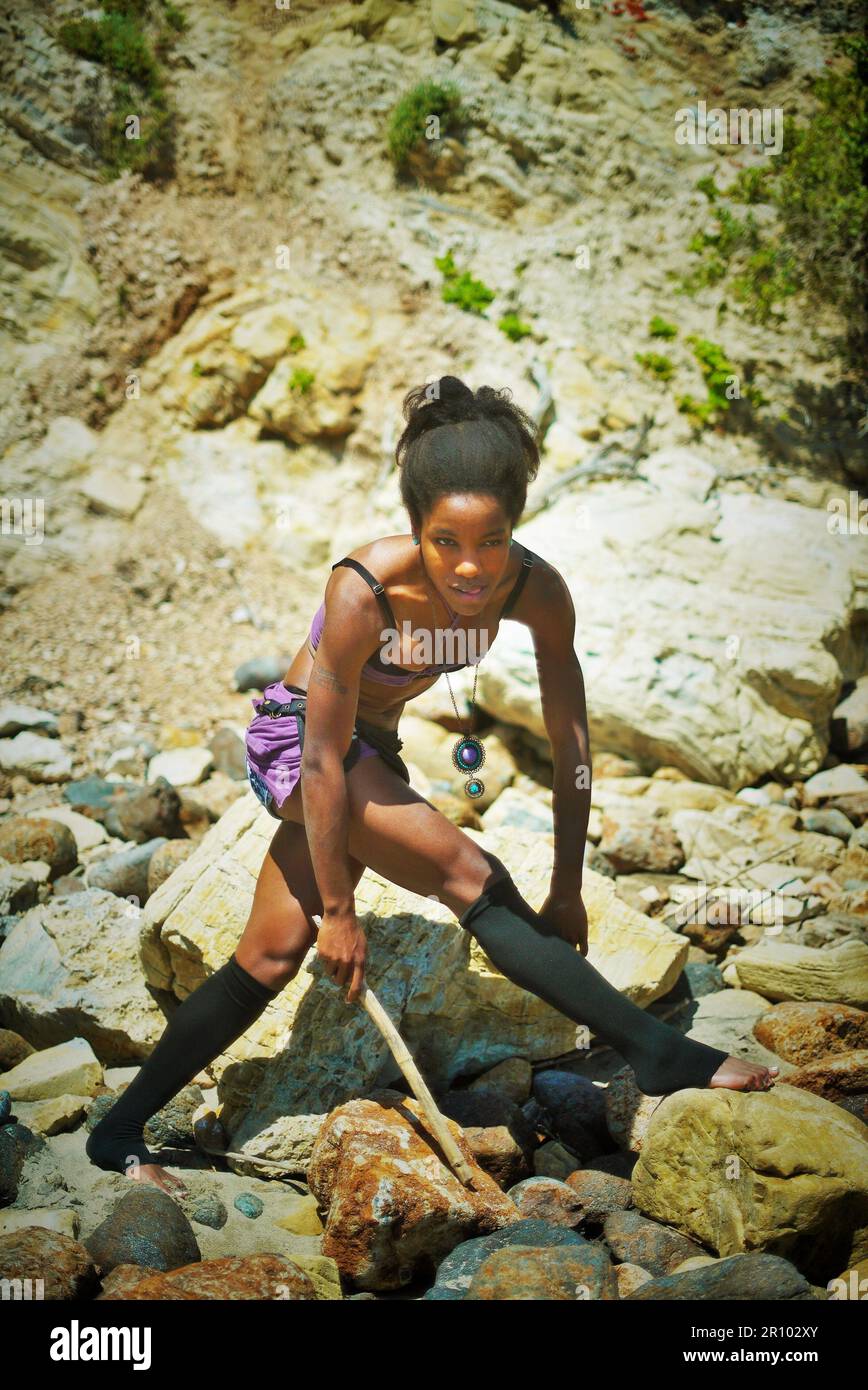 Hermosa mujer negra en ropa púrpura varada en una isla desierta Foto de stock
