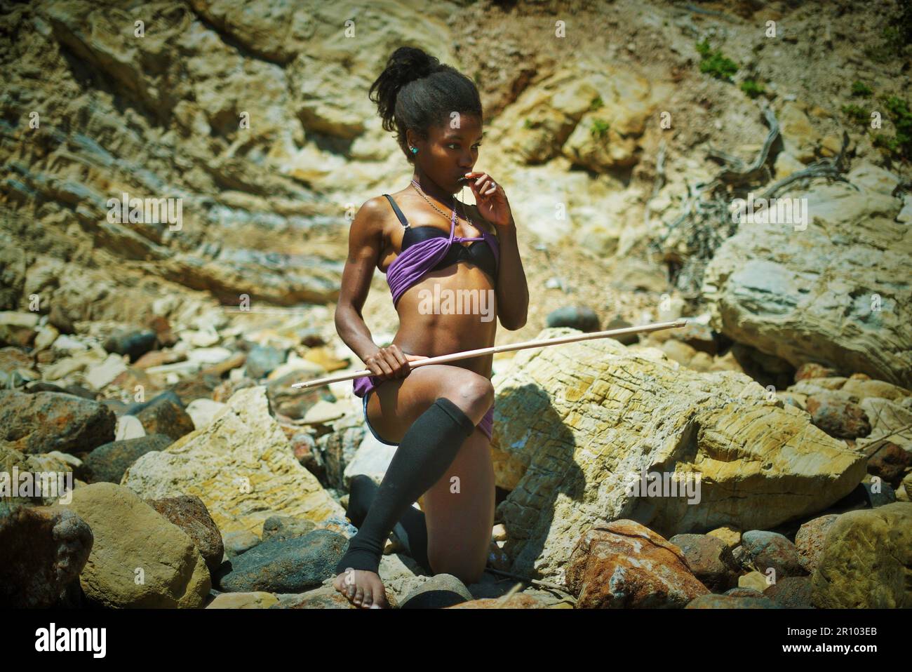 Hermosa mujer negra en ropa púrpura varada en una isla desierta Foto de stock
