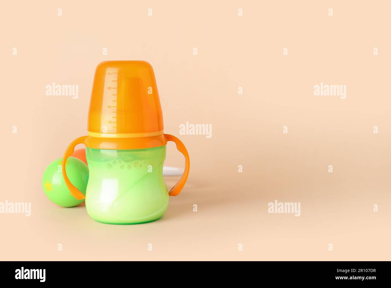Botella de leche para el bebé con sonajero sobre fondo naranja pálido  Fotografía de stock - Alamy