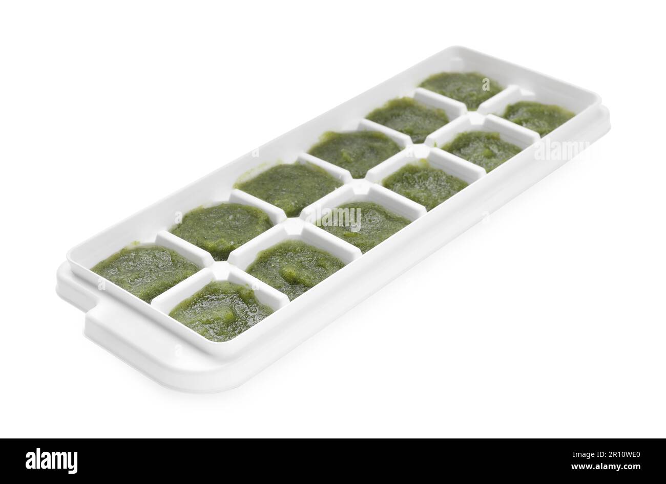 Puré de brócoli en bandeja de cubitos de hielo aislado en blanco. Listo para congelar Foto de stock