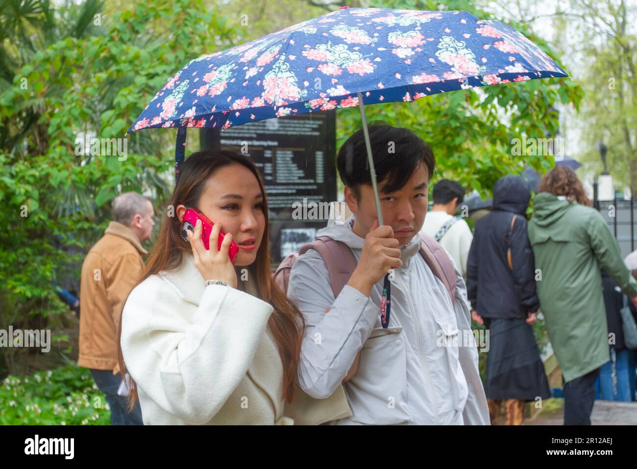 Clima del Reino Unido. Londres, Westminster, Gran Bretaña. Perfil de una pareja asiática de 30s años en Whitehall Gardens Westminster durante una breve lluvia Foto de stock