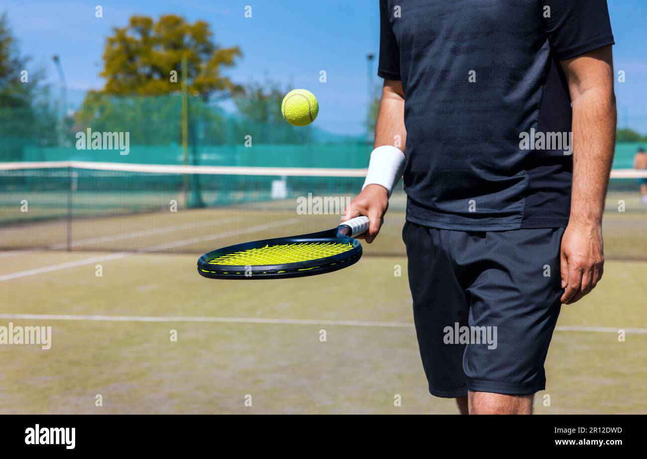 el jugador de tenis rebota la pelota en la raqueta en la cancha de juegos al aire libre Foto de stock