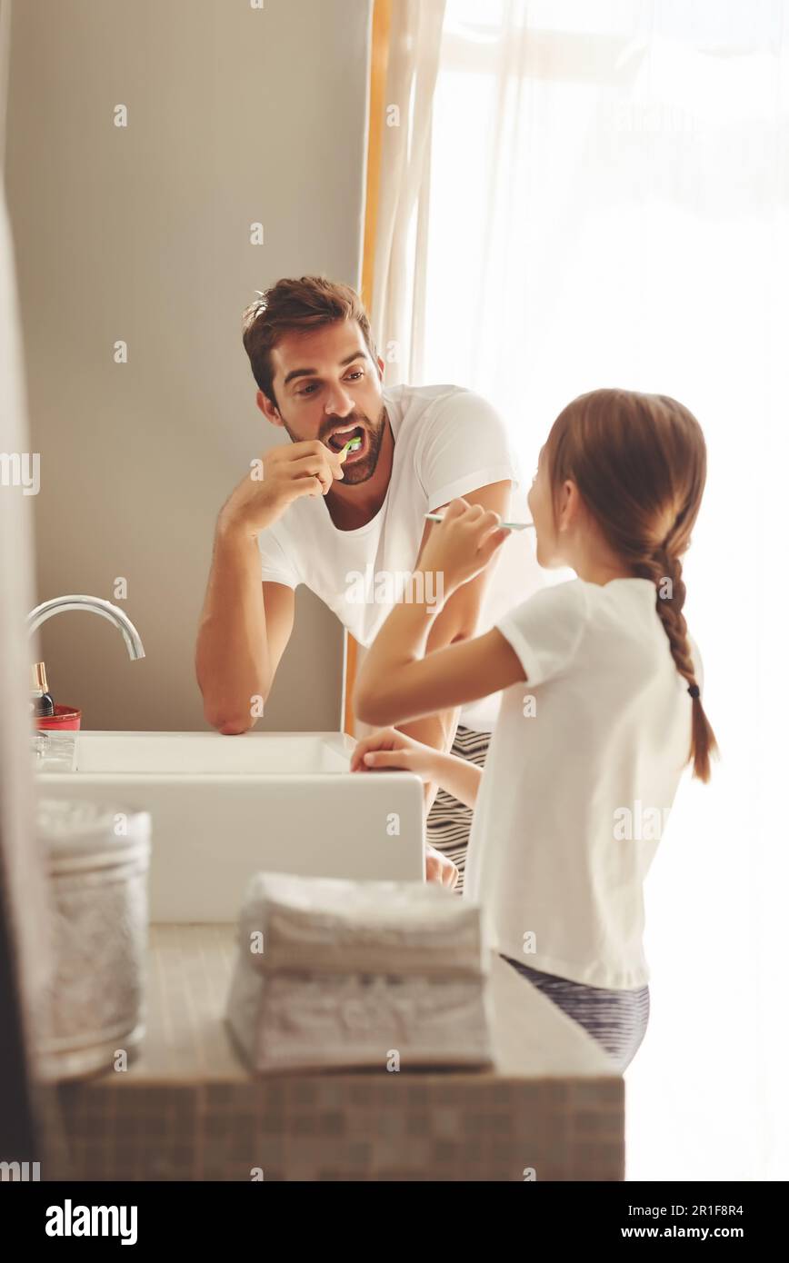 Cepillarse los dientes, padre e hijo aprenden en un baño en casa por la  mañana con la limpieza dental. Higiene oral, niños y papá juntos en una  casa con Fotografía de stock -