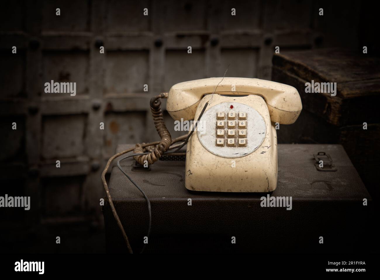 Viejo teléfono beige, antiguo entre radios y papeles viejos Foto de stock