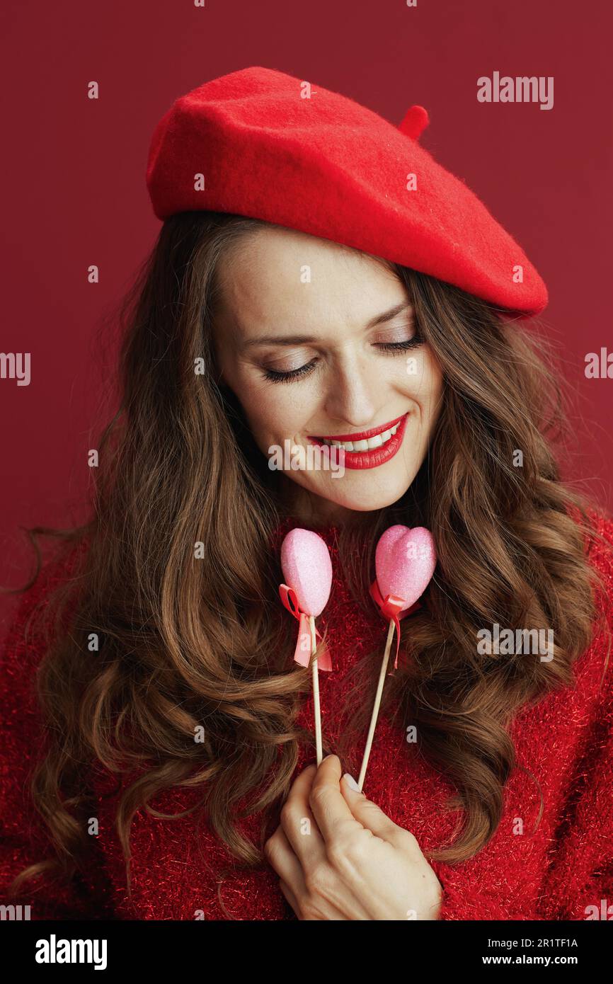 Feliz San Valentín. moderna pensativa en suéter rojo y boina con corazones en palo Fotografía de stock - Alamy