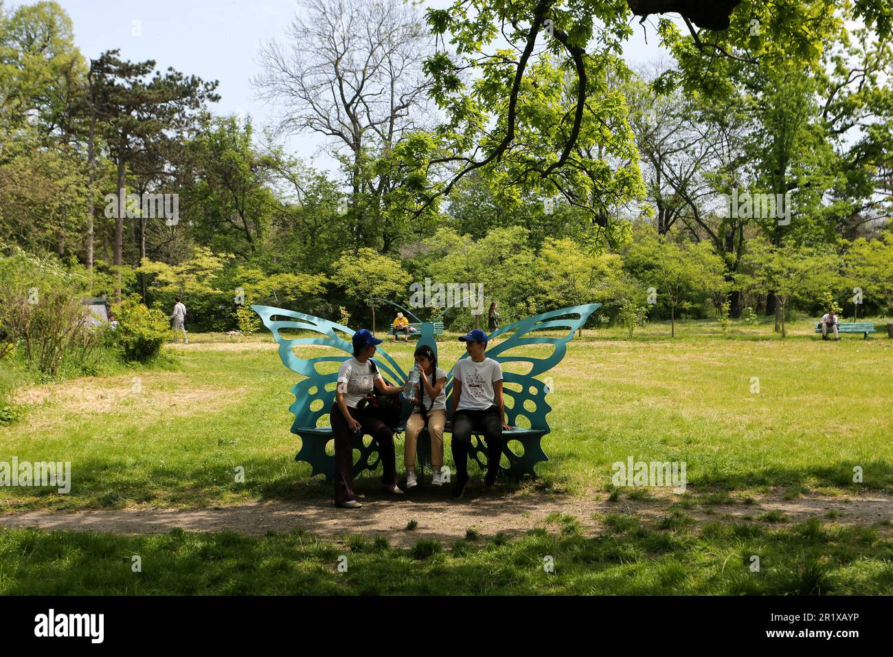 Se ve a la gente sentada en un banco en forma de mariposa en el Jardín Botánico de Odessa (Jardín Botánico de la Universidad Nacional de Odessa Ilya Mechnikov). Jardín Botánico de Odessa (Jardín Botánico de la Universidad Nacional de Odessa Ilya Mechnikov) Más de 3.000 tipos de especies verdes se presentan en el territorio del jardín con un área de aproximadamente 16 hectáreas. El jardín es una subdivisión educativa de la Facultad de Biología de la Universidad, sobre su base se realizan trabajos de diploma y término anualmente, el personal científico del jardín participa en el proceso educativo. El jardín es op Foto de stock