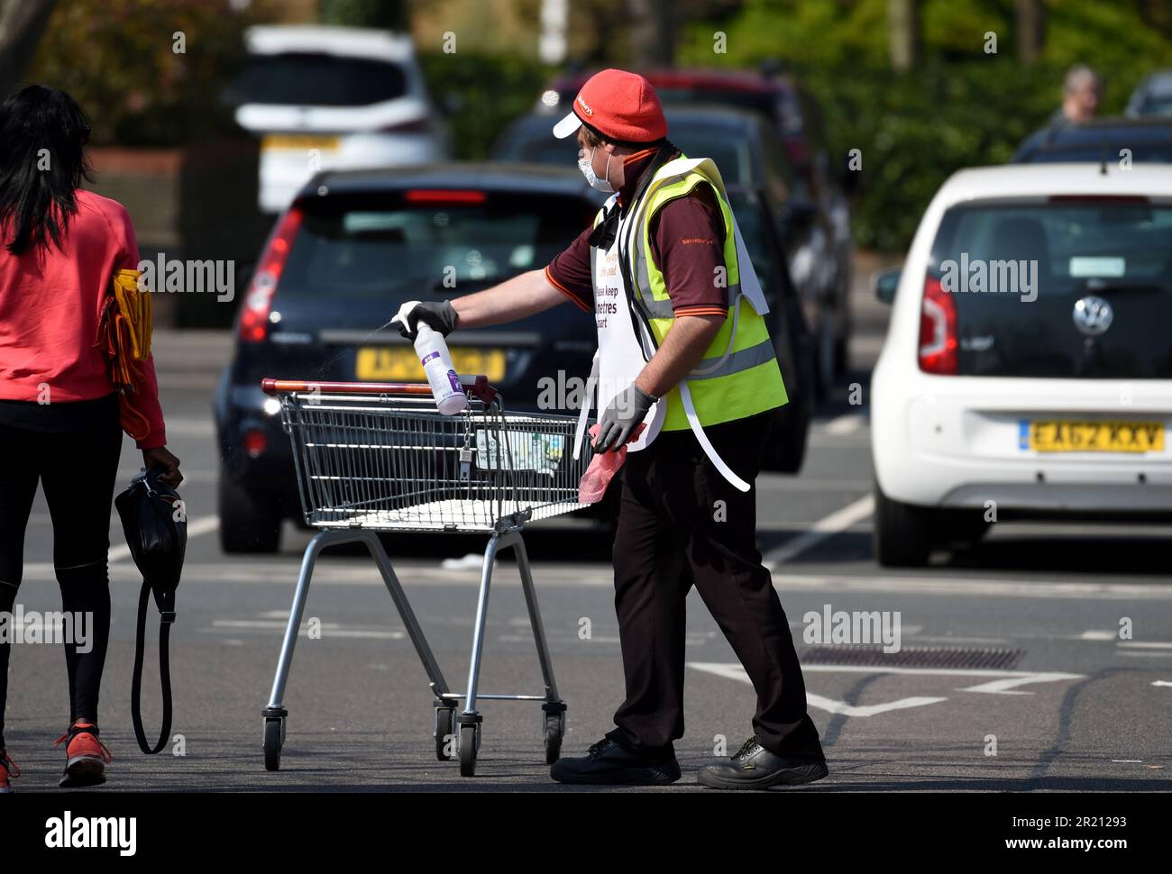 Fotografía de un trabajador de un supermercado desinfectando un carrito