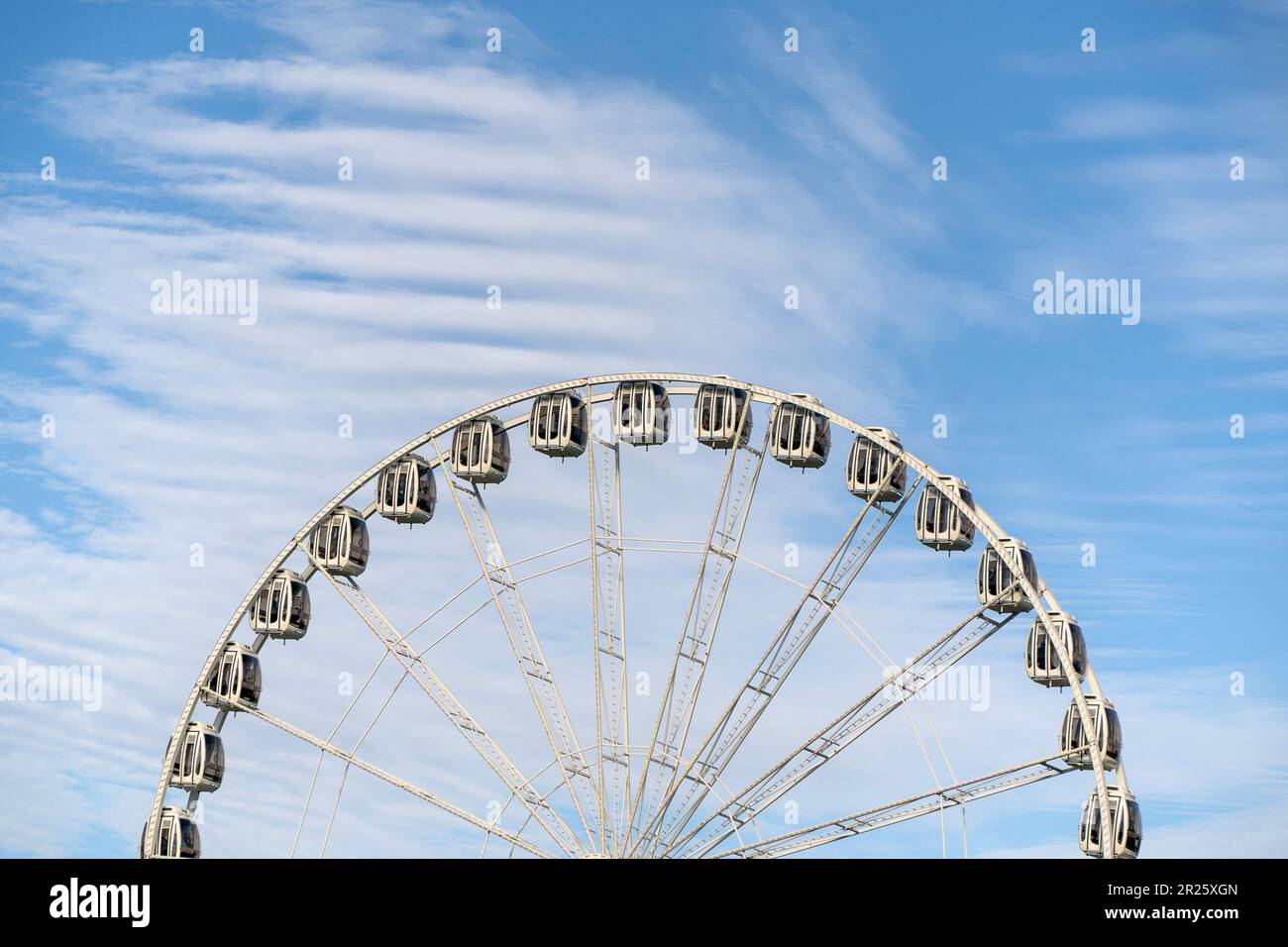 Una vista de la mitad superior de una Rueda de Ferris contra el cielo nublado. Foto de stock
