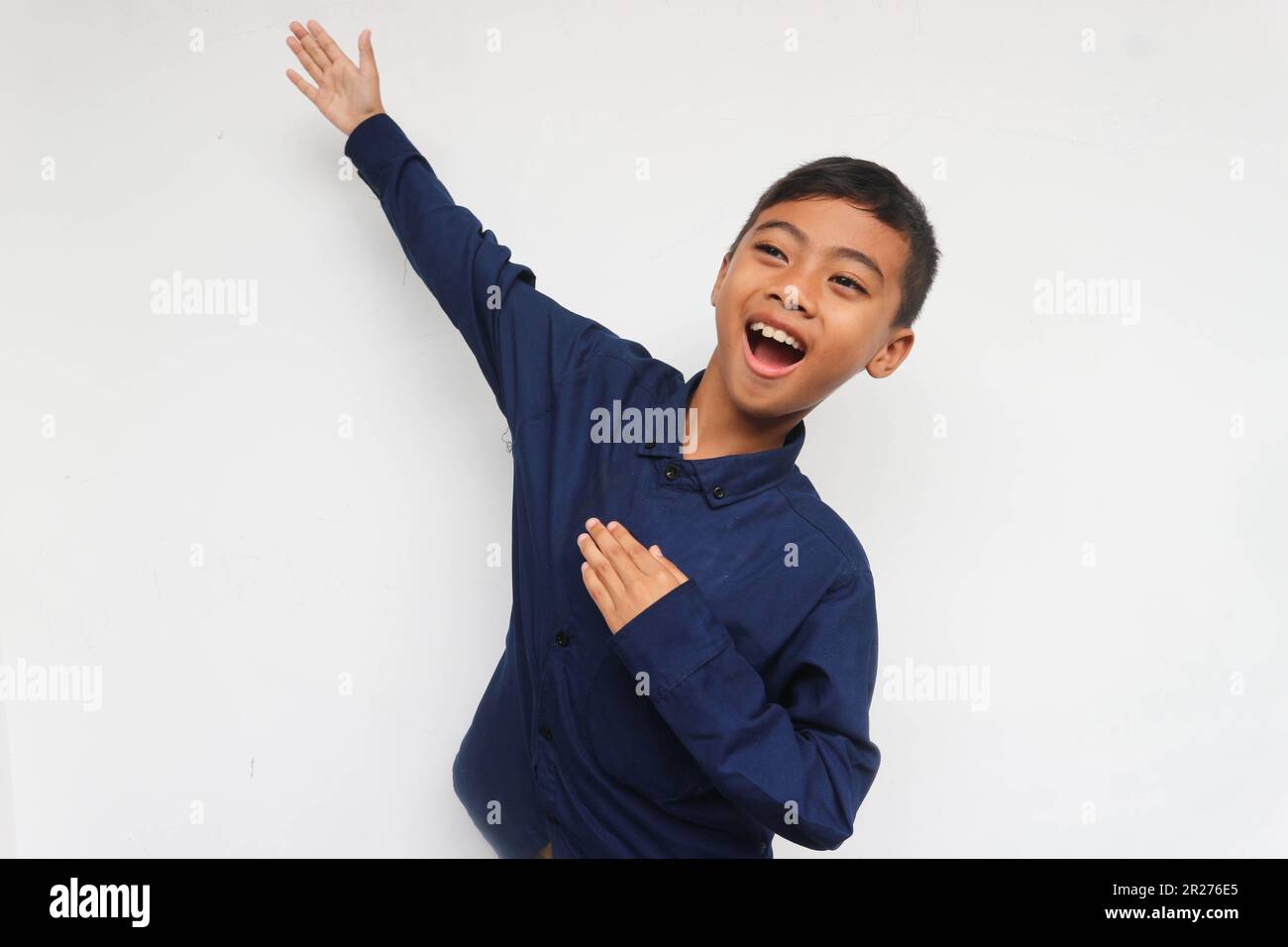 Feliz niño asiático manos arriba brazos levantados de la felicidad aislado en fondo blanco, concepto de éxito ganador de niño emocionado Foto de stock