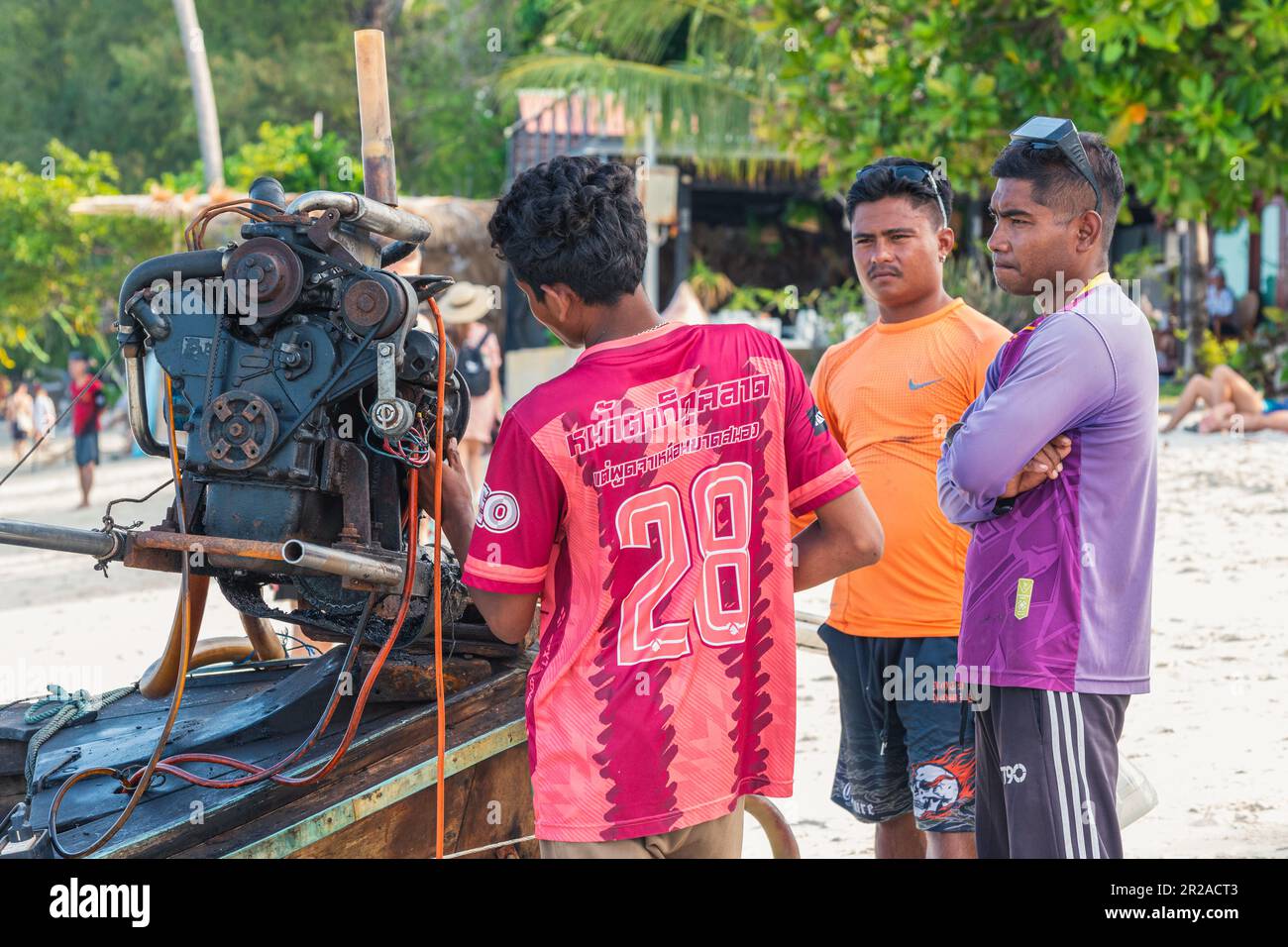 Ko LIPE, TAILANDIA - 9 DE ABRIL DE 2023: Los hombres discuten el motor de un barco de cola larga en la playa. Foto de stock