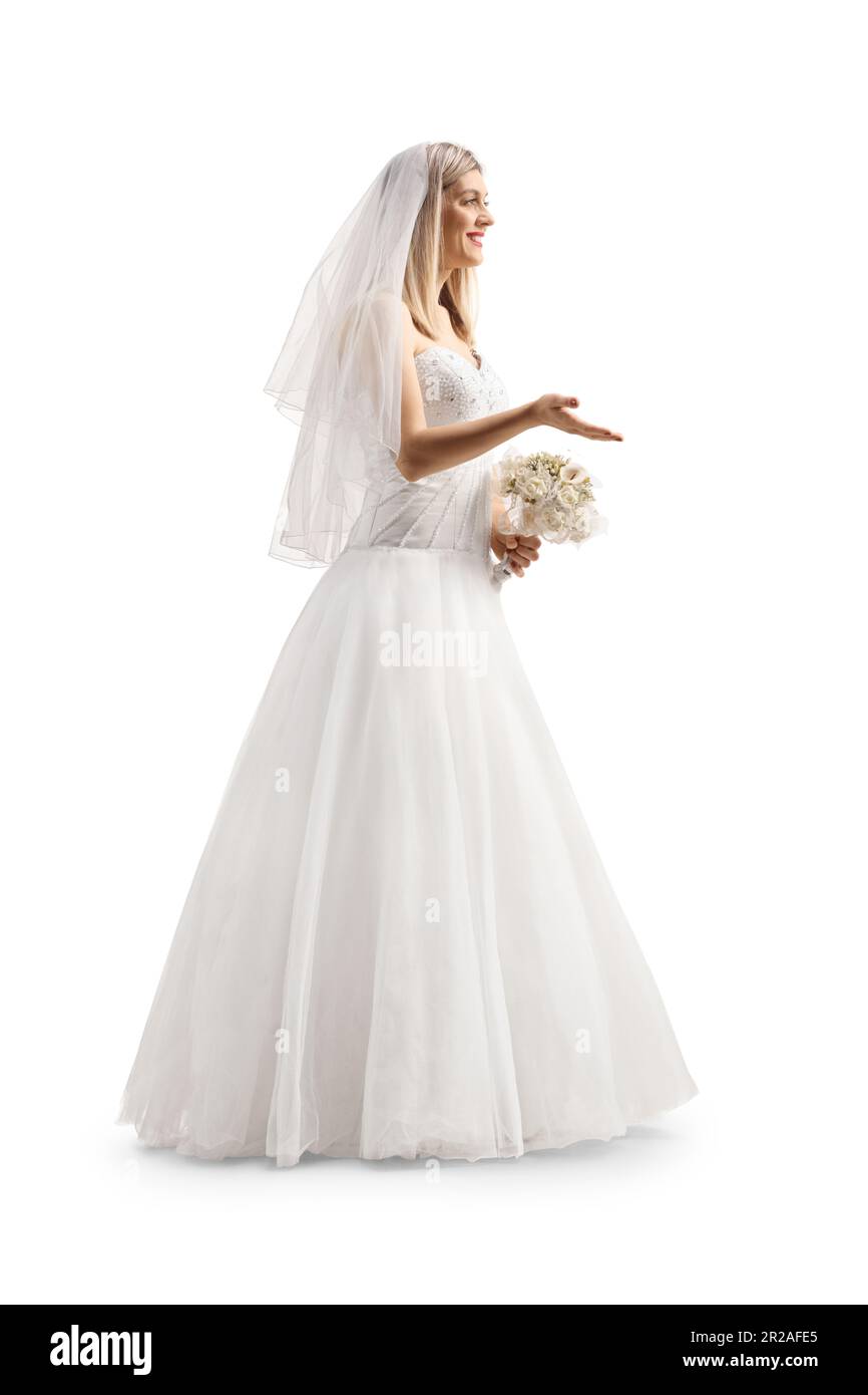 Foto de perfil de longitud completa de una novia con un velo sosteniendo un ramo nupcial y gesticulando con la mano aislada sobre fondo blanco Foto de stock