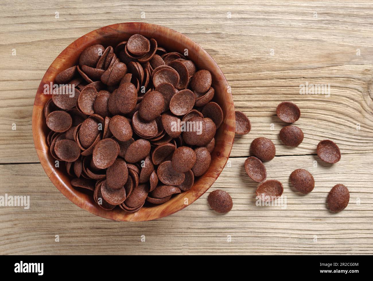 Directamente encima de la vista de los copos de maíz de chocolate en tazón sobre fondo de madera primer plano Foto de stock