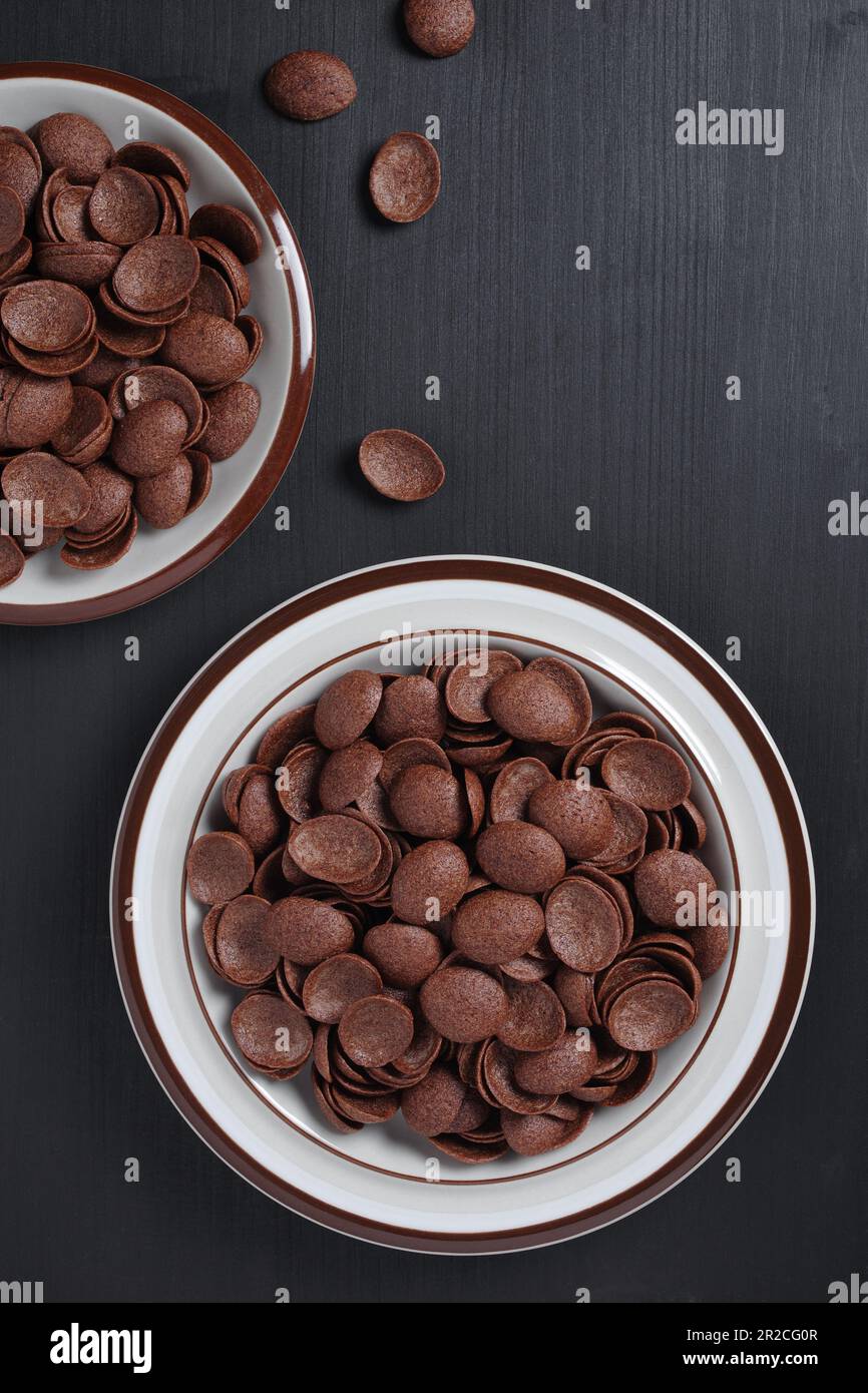 Directamente encima de la vista del desayuno de cereales de chocolate en plato sobre fondo de madera negro Foto de stock