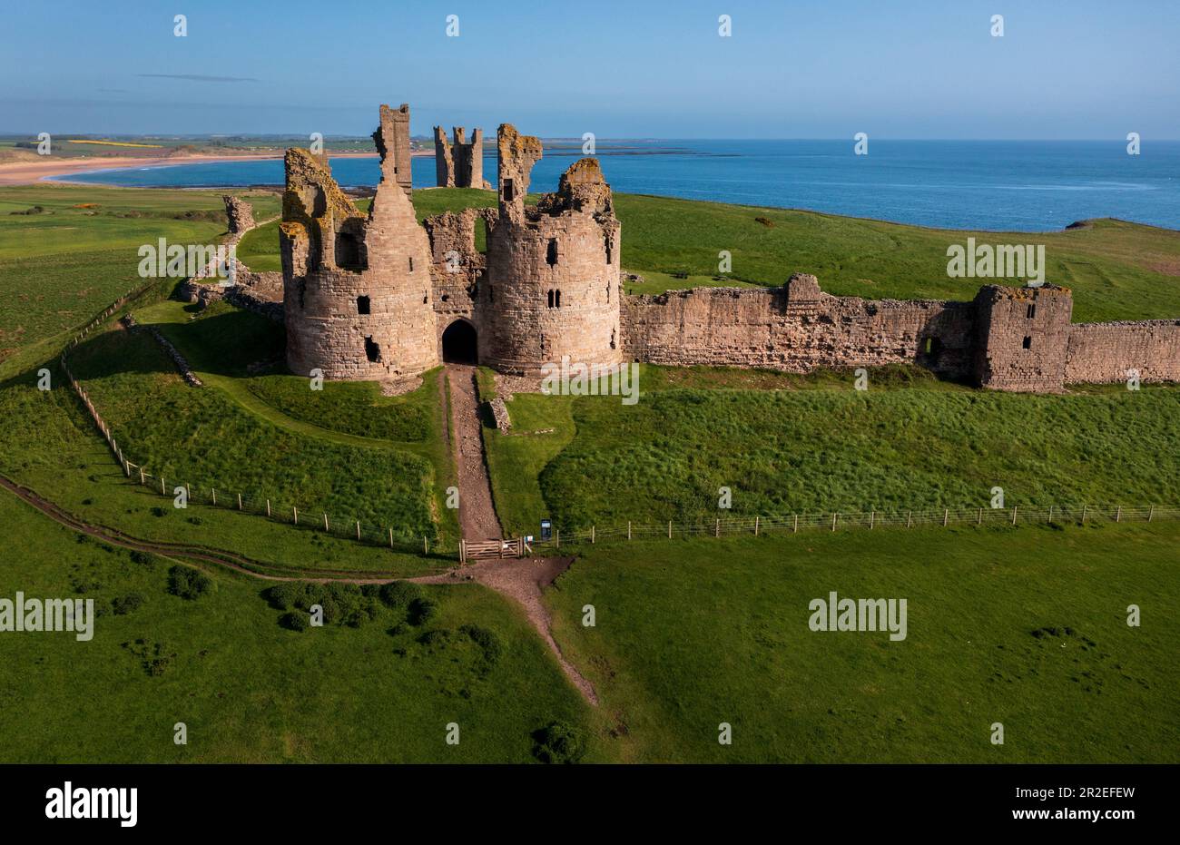 Vista aérea de los restos en ruinas del castillo de Dunstanburgh en la costa de Northumberland, noreste de Inglaterra, Reino Unido Foto de stock