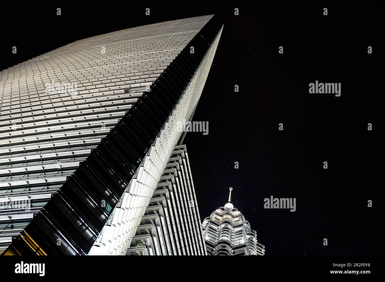 Vista nocturna de un rascacielos iluminado y la Torre Petronas desde una perspectiva inusual, Kuala Lumpur, Malasia Foto de stock