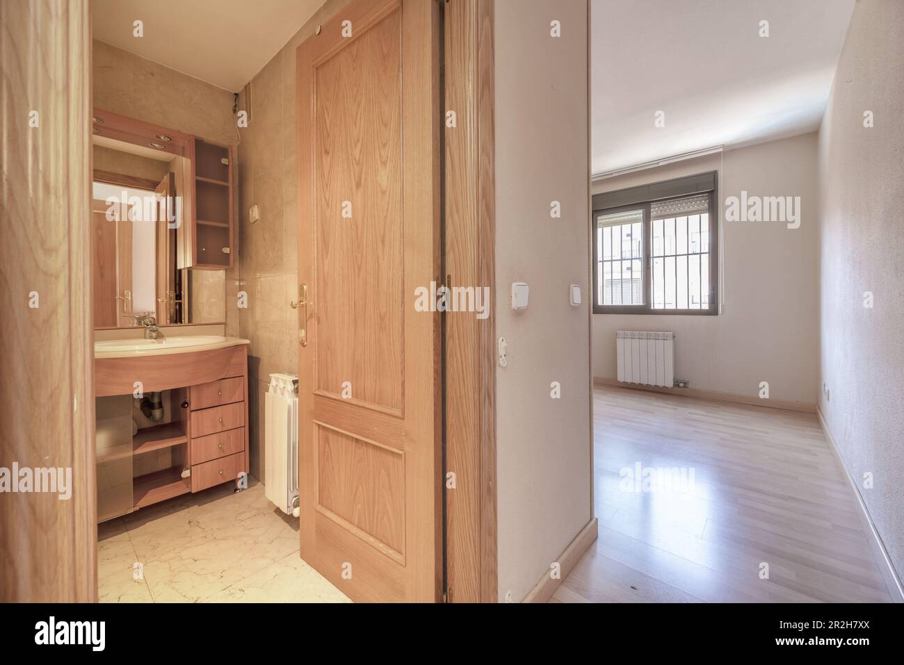 Una habitación con baño en suite amueblada con espejo integrado y ventanas de aluminio con rejas Foto de stock