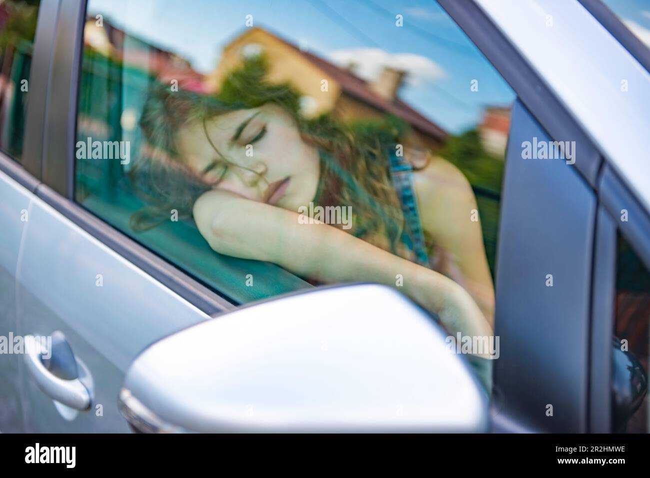 Chica cansada durmiendo en coche, vista desde fuera Foto de stock