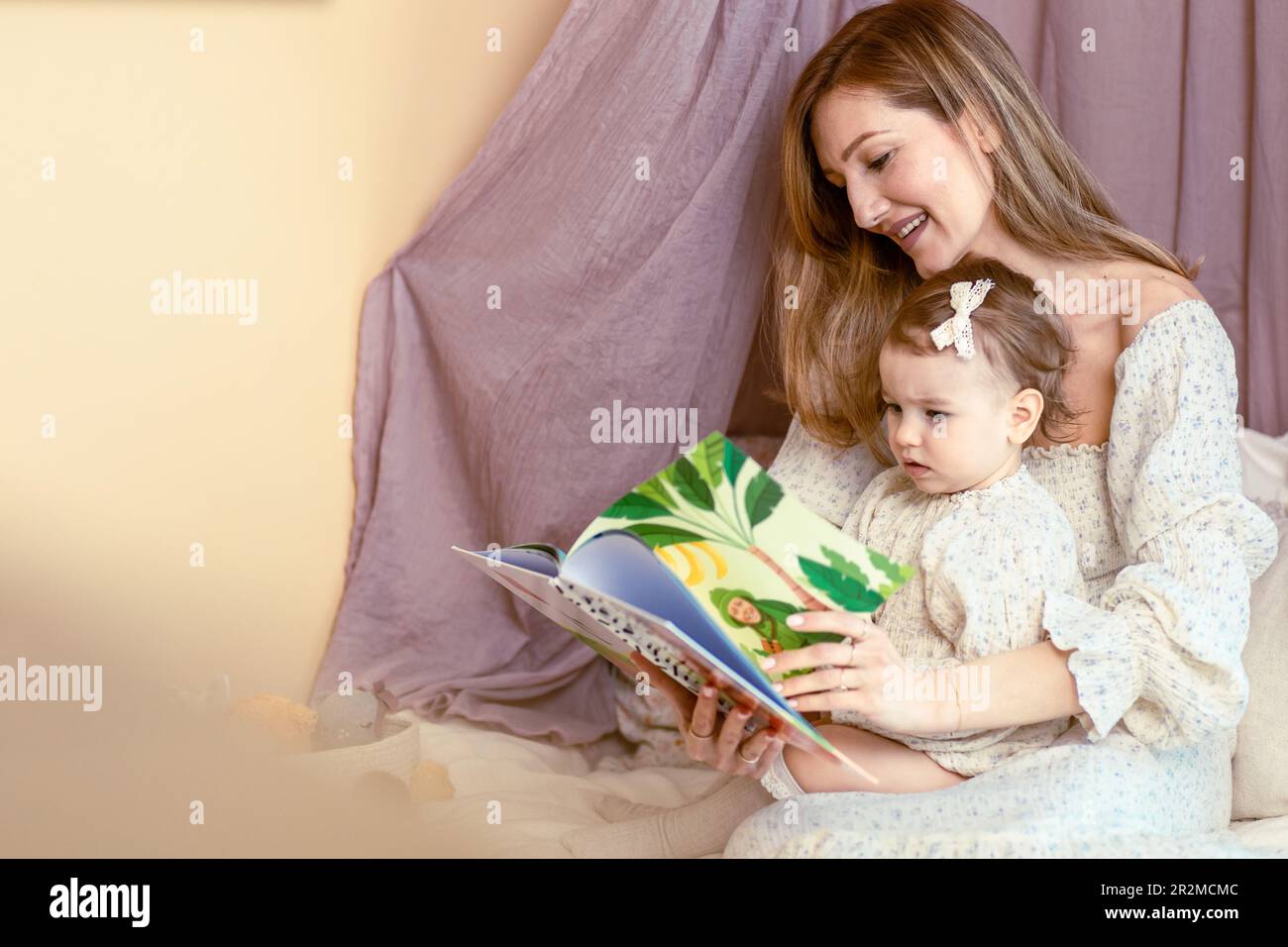Mamá joven leyendo con su niña de un año Foto de stock