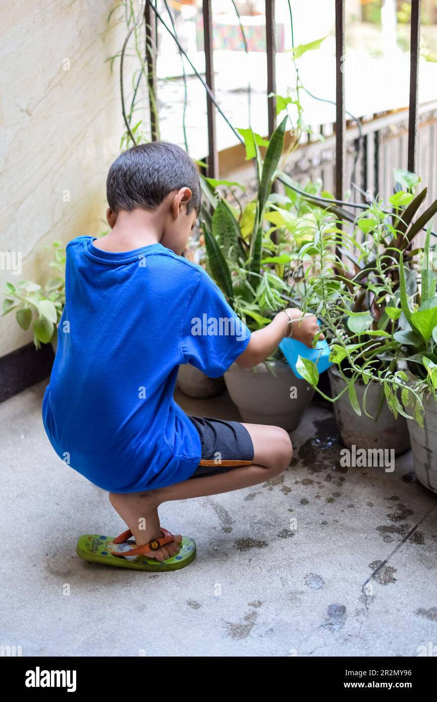 Lindo niño asiático de 5 años está regando la planta en las macetas  ubicadas en el balcón de la casa. El amor del niño pequeño dulce para la  madre naturaleza durante w