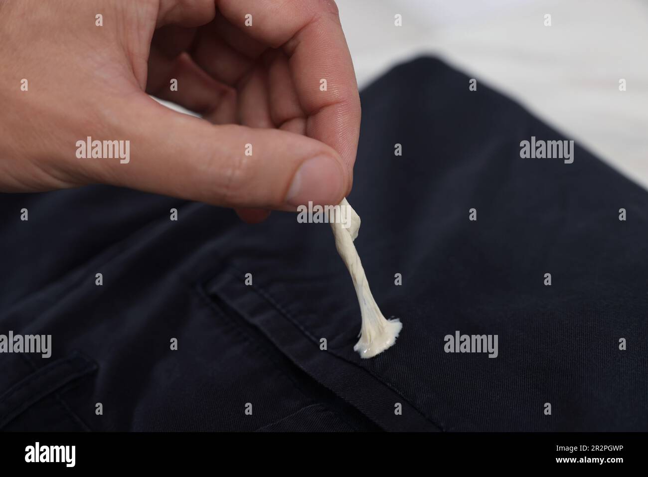 Hombre quitando chicle de jeans negros sobre fondo blanco, closeup de stock - Alamy