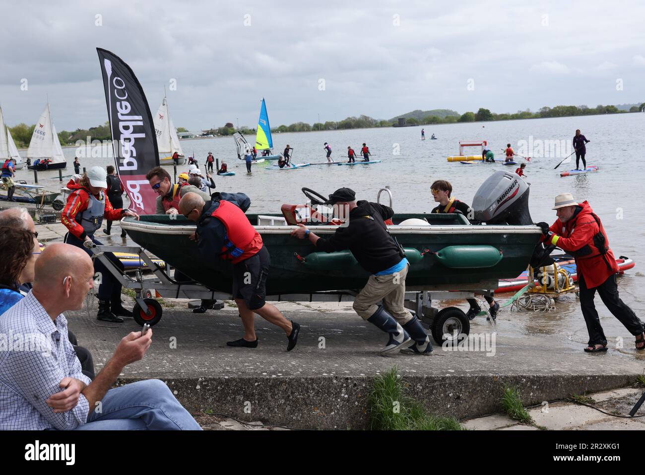 Mayo 2023 - Muchas manos hacen trabajo ligero, arrastrando un barco a tierra como el festival de la vela en el embalse de Cheddar, Somerset, Inglaterra, Reino Unido. Foto de stock