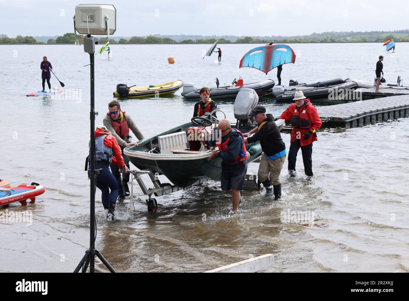 Mayo 2023 - Muchas manos hacen trabajo ligero, arrastrando un barco a tierra como el festival de la vela en el embalse de Cheddar, Somerset, Inglaterra, Reino Unido. Foto de stock