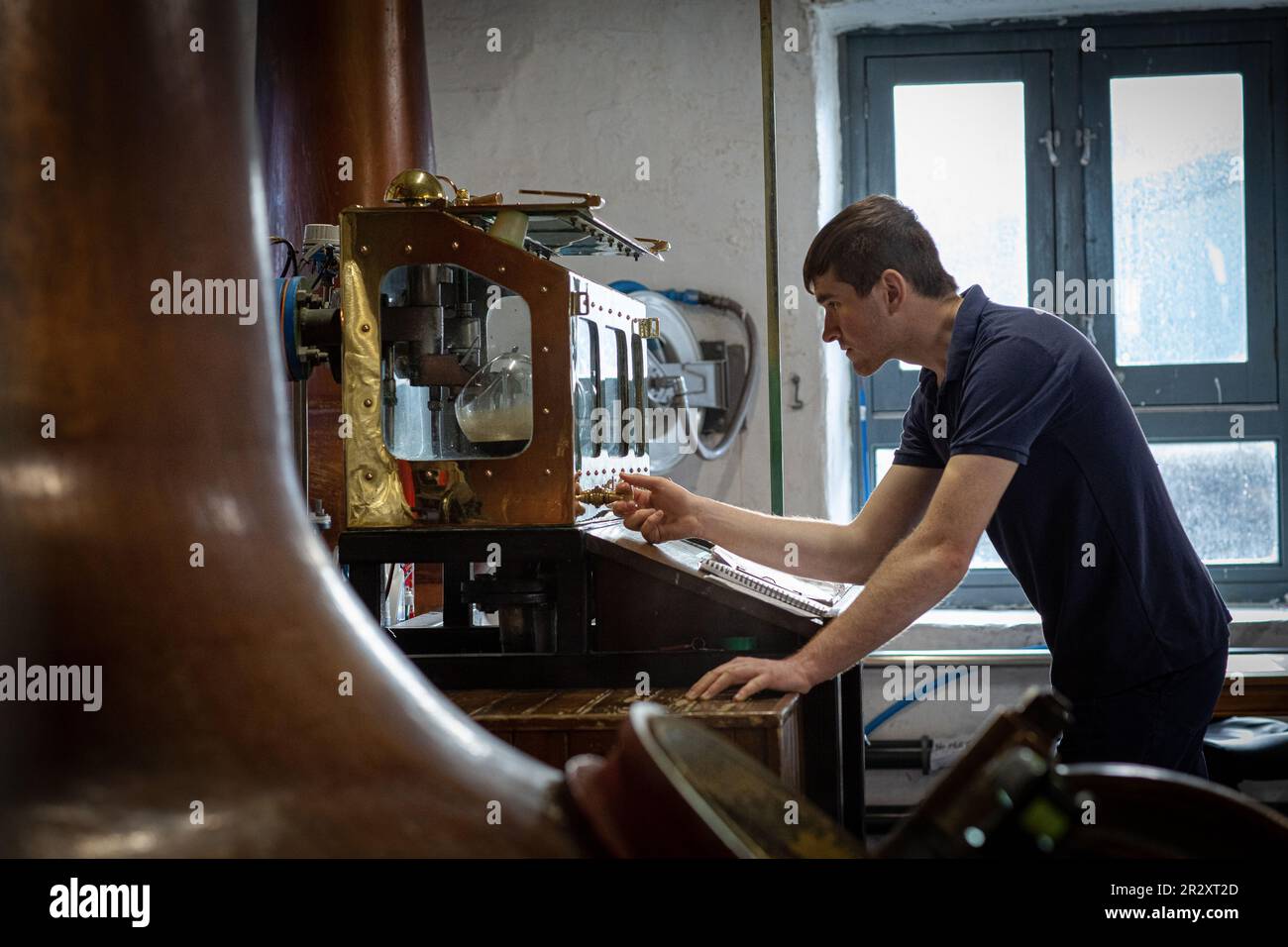 ISLAY, ESCOCIA - La destilería de whisky Kilchoman todavía el hombre comprueba los niveles de alcohol en el Spirit Safe. Foto de stock