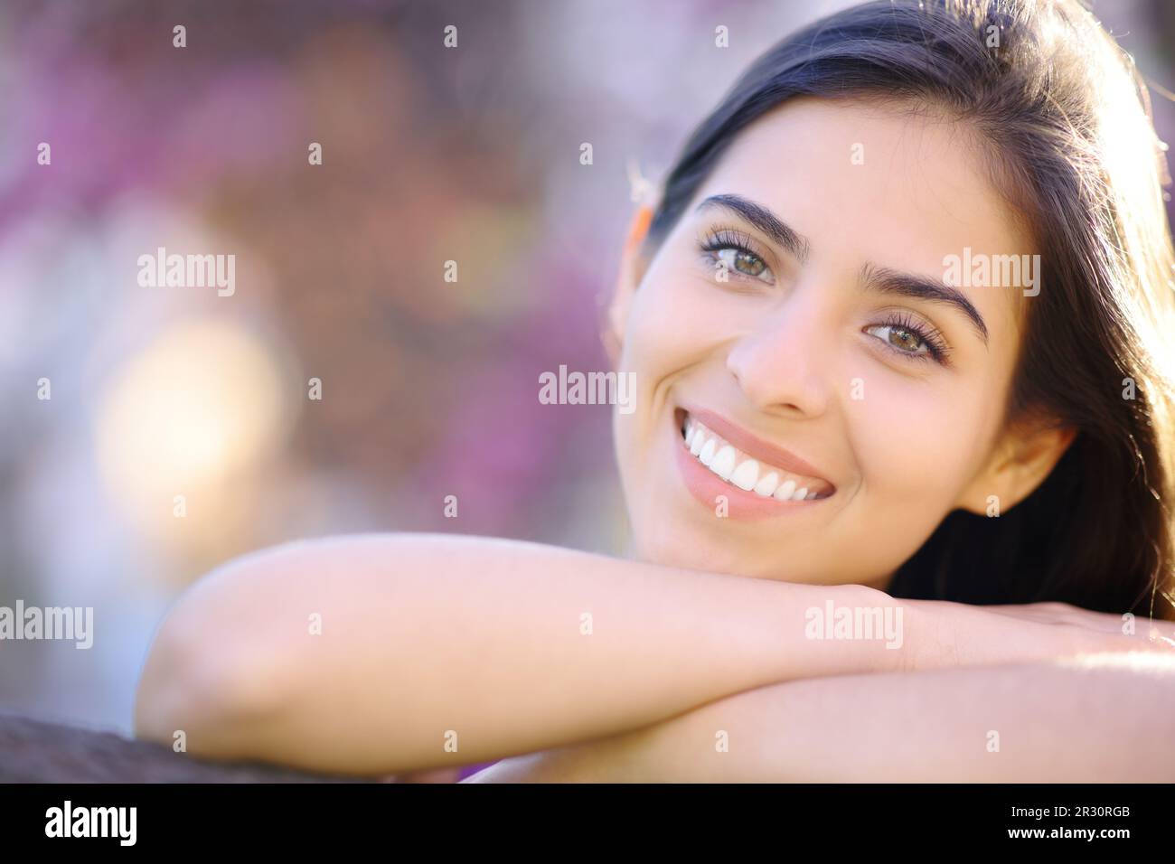 Vista frontal de una mujer hermosa con dientes blancos perfectos sonriendo a usted en un parque Foto de stock