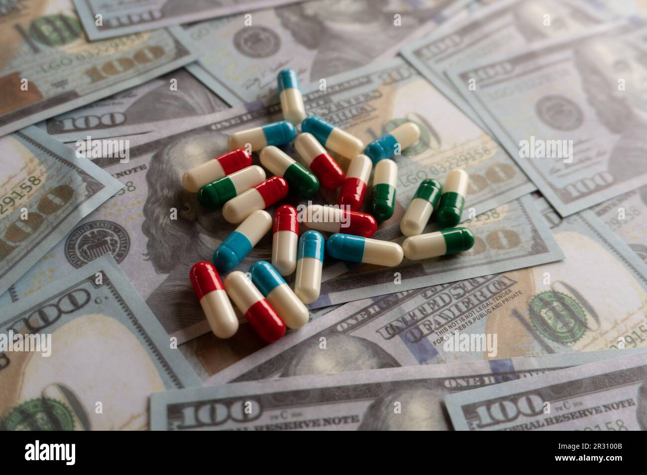 Enfoque selectivo de la imagen de píldoras coloridas en la parte superior del dinero. Gastos médicos y concepto de la industria farmacéutica Foto de stock