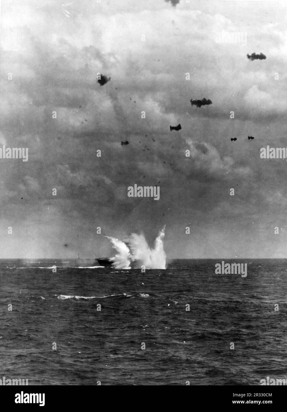 Un avión kamikaze golpea el agua del cuarto de estribor de los Estados Unidos Portaaviones de la Armada USS Enterprise (CV-6), durante operaciones frente a Okinawa, 11 de abril de 1945. Cuando Japón se enfrentaba a la derrota a finales de 1944, decidió destruir barcos estadounidenses con bombas suicidas, conocidas como Kamikaze. Estos ataques eran un arma física y psicológica potente y hundieron un total de 47 barcos a un costo de más de 3000 pilotos y aviones. A finales de 1944 la Marina de los Estados Unidos era lo suficientemente grande como para que las pérdidas fueran insignificantes y no alteraran el curso de la guerra. Foto de stock