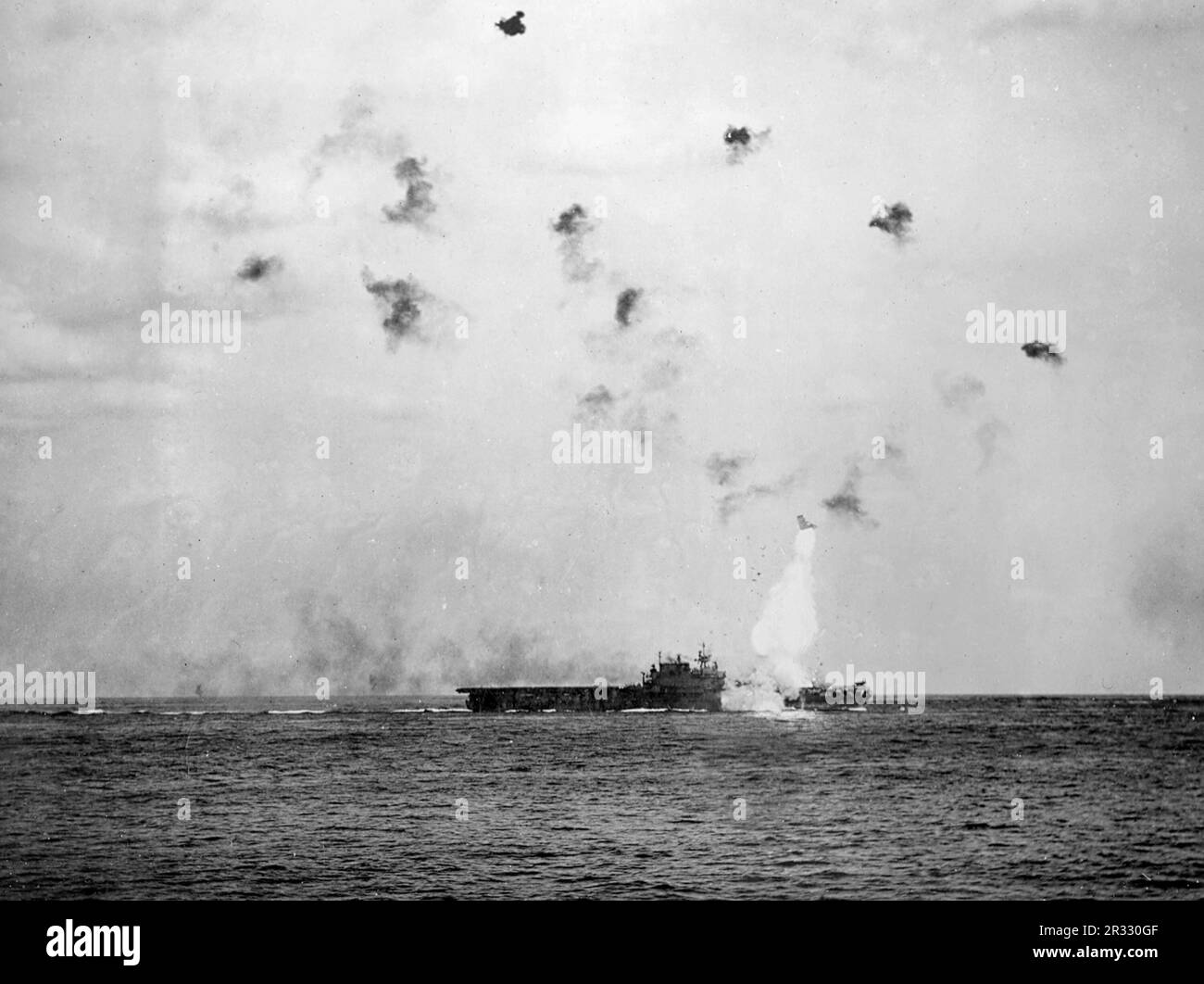 Estados Unidos El portaaviones de la Armada USS Enterprise (CV-6) en llamas después de que el barco fuera golpeado por un kamikaze frente a Kyushu el 14th de mayo de 1945. El elevador delantero, que pesa muchas toneladas, se puede ver arrojado por la explosión. Foto de stock