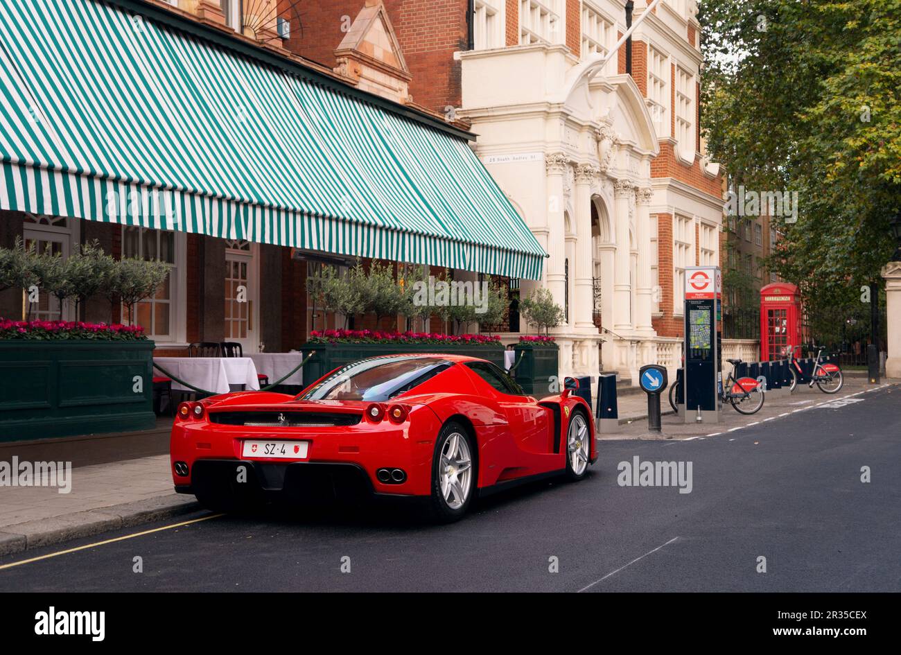 Un Ferrari Enzo rojo estacionado en una calle frondosa en Mayfair, Londres. Foto de stock