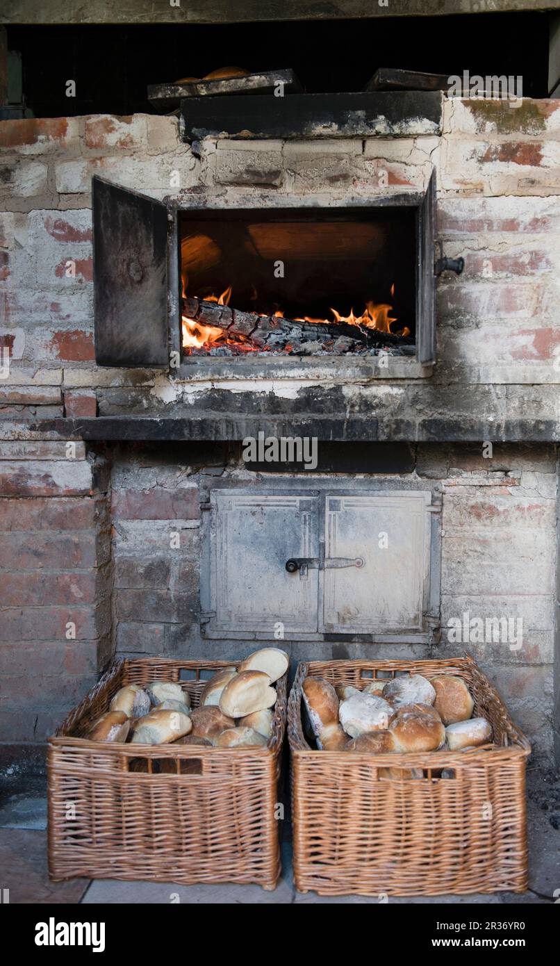 Una estufa de madera brillante y panecillos recién horneados en cestas de mimbre Foto de stock