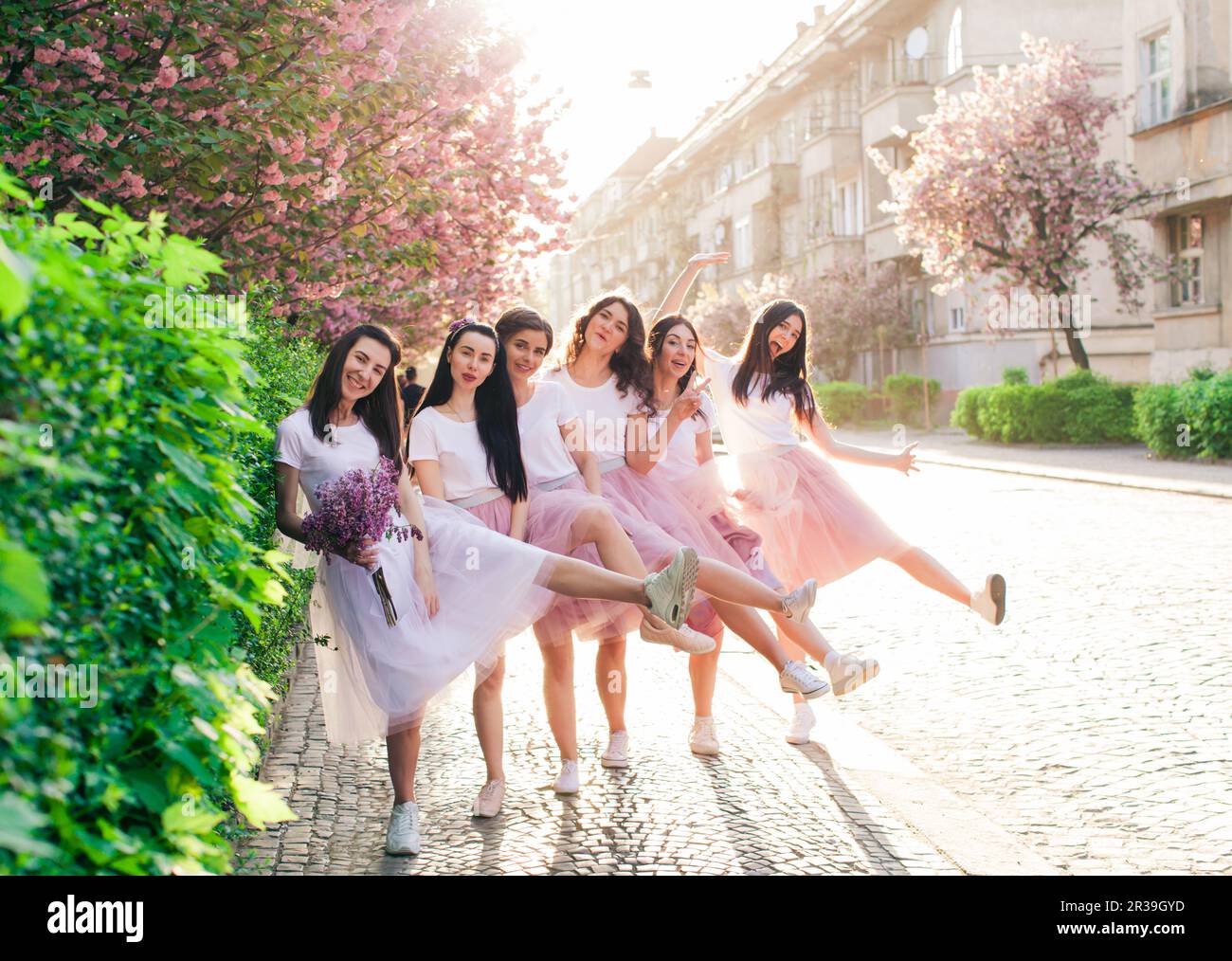 Chicas divertidas stylsh en vestidos lila de moda celebrando despedida de soltera Foto de stock