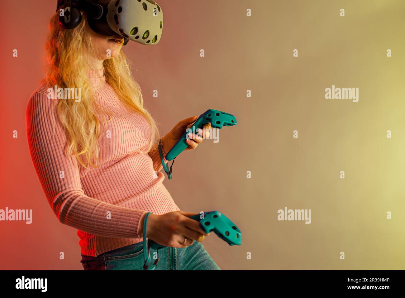 Vista lateral de la mujer con el pelo rojo con gafas de realidad virtual  mientras juega videojuegos con controlador inalámbrico.