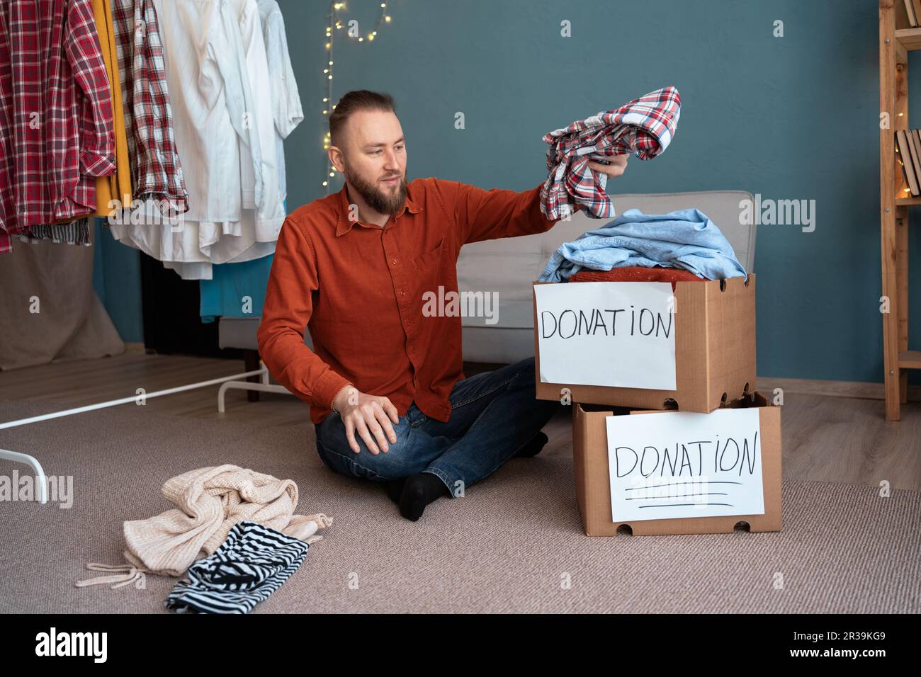 Concepto de donación y caridad. Hombre que embala una caja de donación con la ropa. Ayudar a las personas pobres y necesitadas. Foto de stock