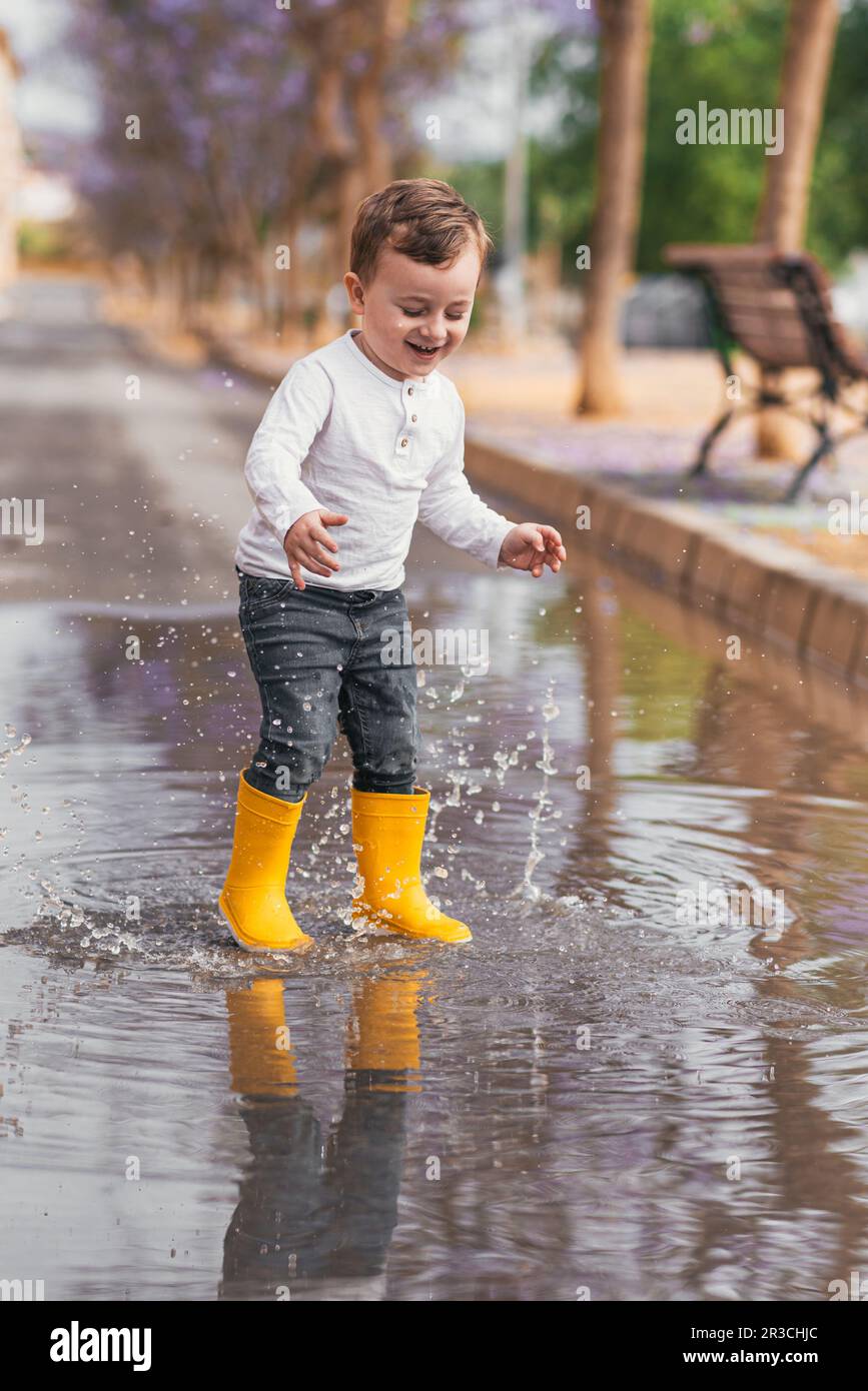 Fotos de Niño Pequeño Con Botas Goma Amarillas Saltando Charco Agua Día -  Imagen de © mary_smn #388806400