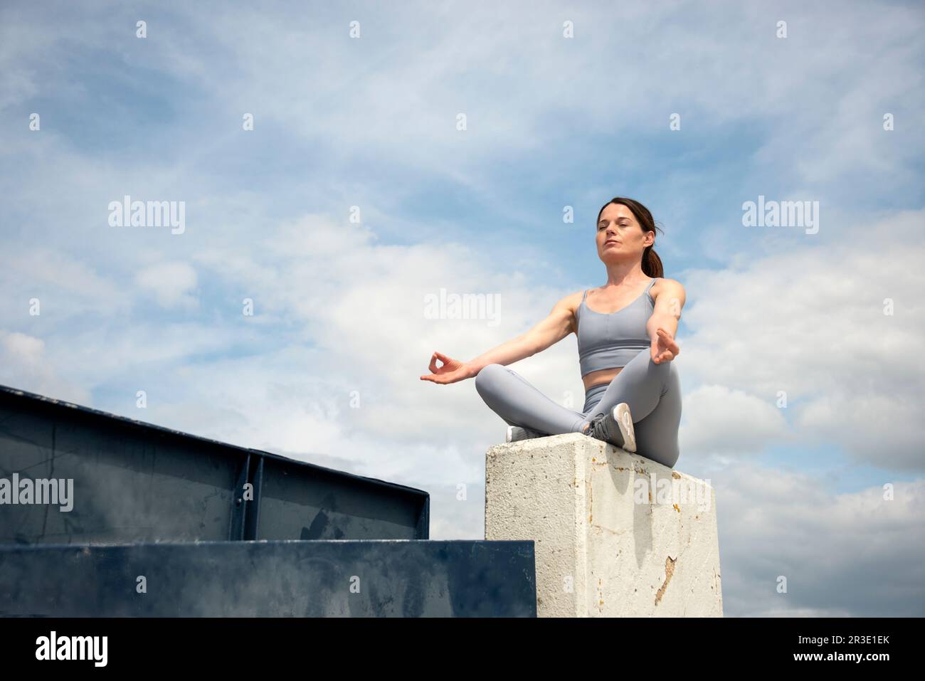mujer adulta media deportiva sentada fuera meditando, entorno urbano. Foto de stock