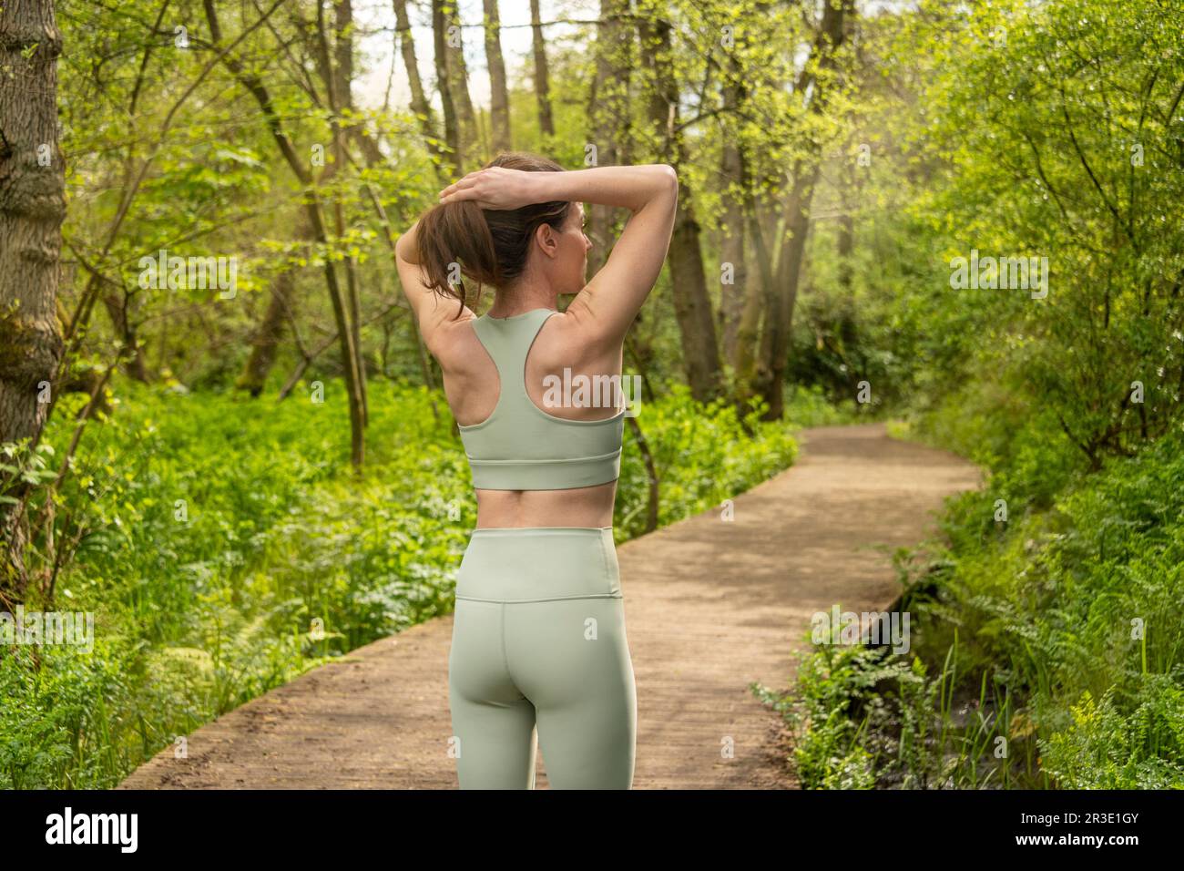 mujer deportiva atando su cabello antes de correr en el parque Foto de stock