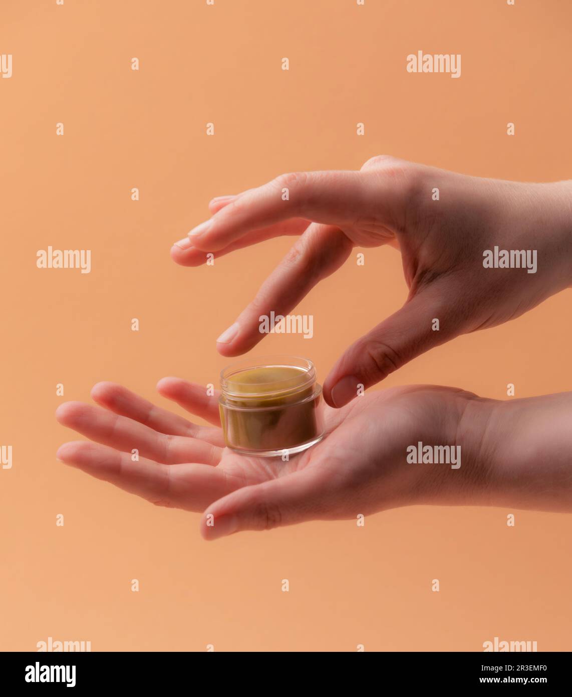 Bálsamo labial ecológico natural con manos femeninas sobre beige Foto de stock