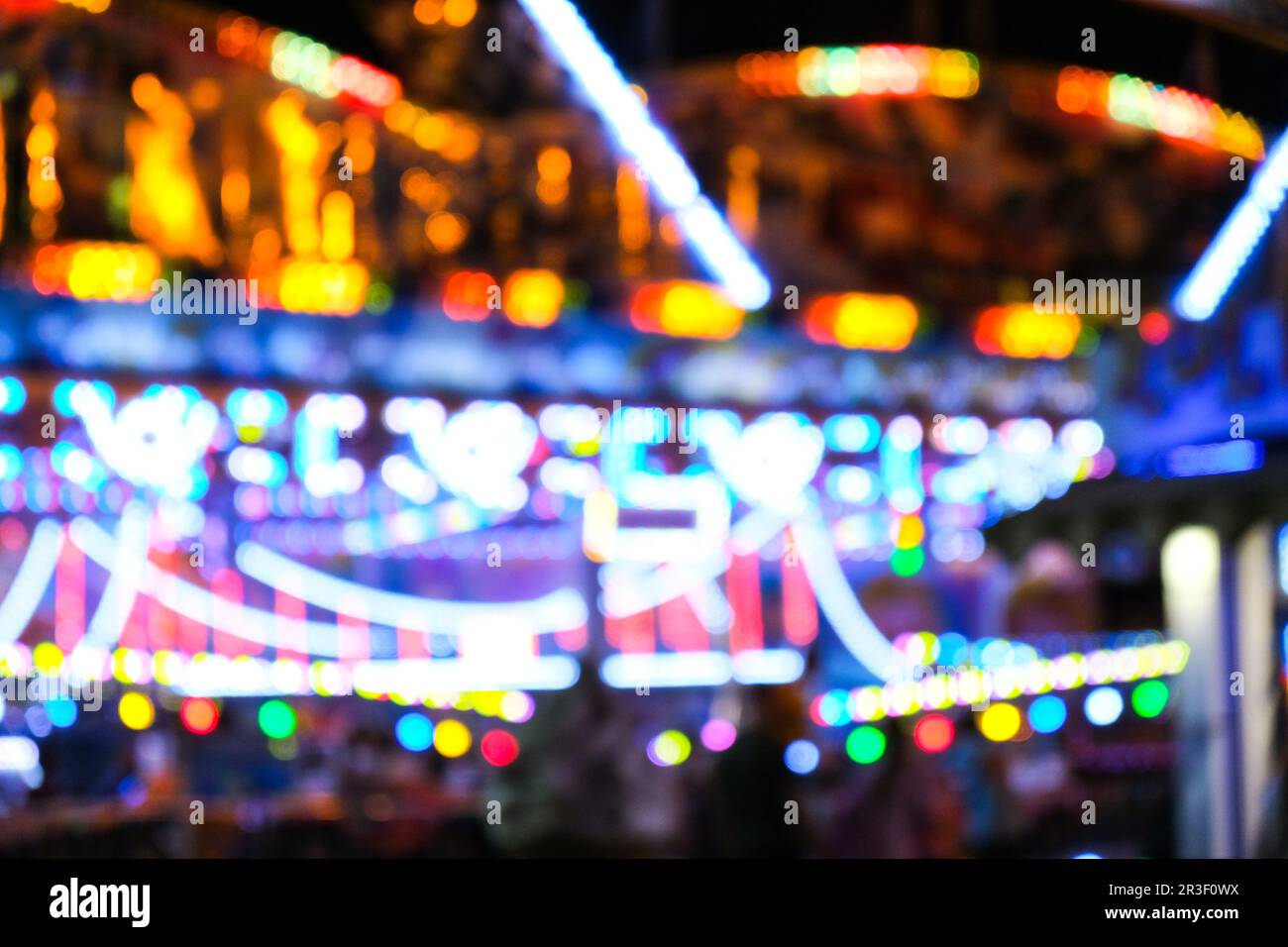 Las luces brillantes desfocadas parpadean en un divertido carnaval por la noche. Parque de atracciones Bokeh Luces por la noche. Entretenimiento nocturno Foto de stock
