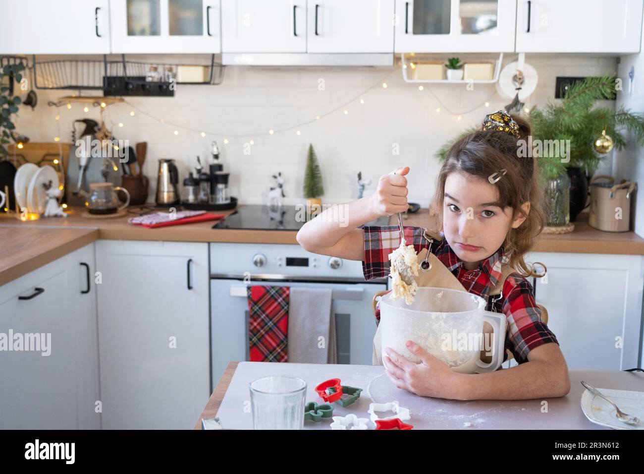 Hija aprendiendo a cocinar ayuda en la cocina blanca amasar la masa en el tazón para pan de jengibre y galletas para Navidad y n Foto de stock