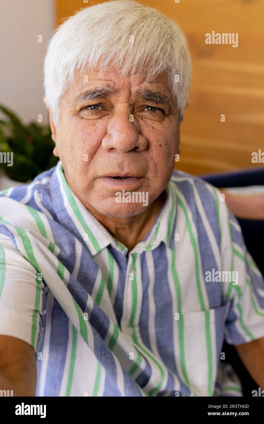Hombre biracial senior en camisa a rayas haciendo videollamada sentado en casa Foto de stock
