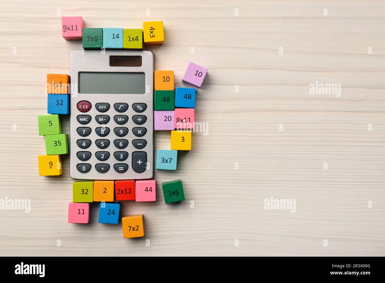 Cubos de colores con números y multiplicaciones cerca de la calculadora en  la mesa de madera blanca, plana. Espacio para texto Fotografía de stock -  Alamy
