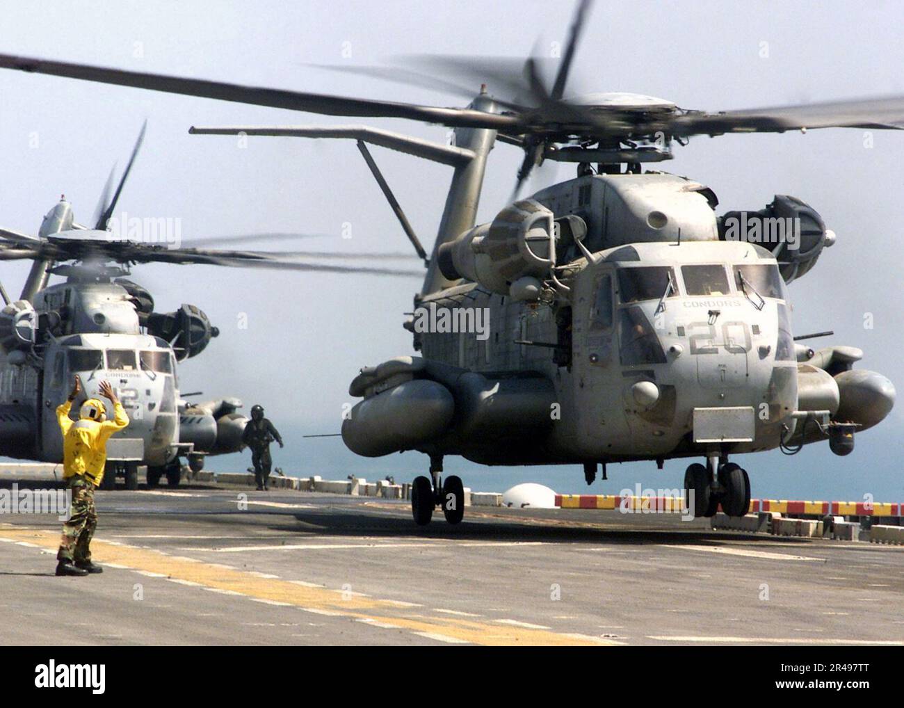 La Marina de LOS EE.UU. Un compañero de Boatswain de Aviación señala los lanzamientos de un CH-53D Sea Stallion desde la cubierta de vuelo de la nave Foto de stock