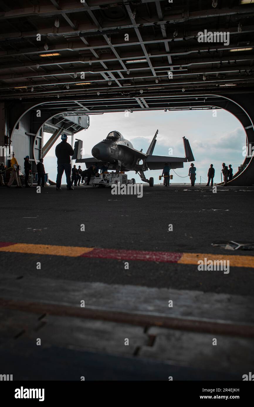 Los marineros asignados al departamento aéreo a bordo del portaaviones clase Nimitz USS George Washington (CVN 73) trasladan un avión de entrenamiento F/A-18C Hornet a la bahía del hangar a bordo del USS George Washington clase Nimitz (CVN 73) en Newport News, Virginia, el 28 de marzo de 2023. George Washington está siendo sometido a una revisión del complejo de reabastecimiento de combustible (RCOH) en Newport News Shipbuilding. RCOH es un proyecto de varios años realizado solo una vez durante los 50 años de vida útil de un portaaviones que incluye repostar los dos reactores nucleares del barco, así como reparaciones significativas, mejoras y modernización. (EE. UU Foto de la Marina de Mass Comm Foto de stock