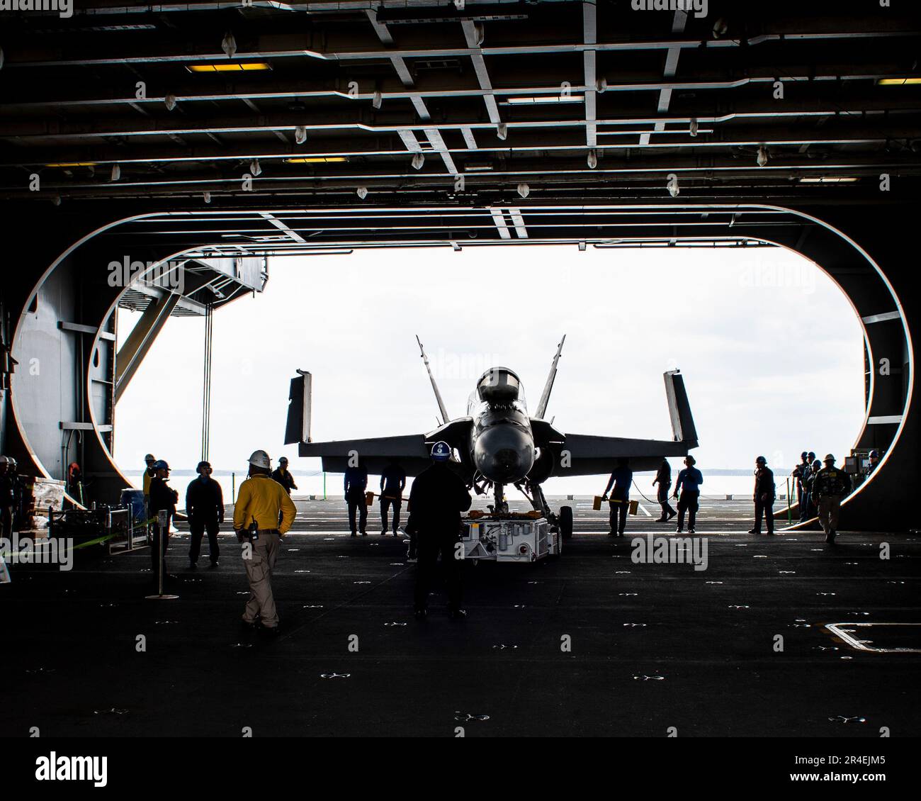 Los marineros asignados al departamento aéreo a bordo del portaaviones clase Nimitz USS George Washington (CVN 73) trasladan un avión de entrenamiento F/A-18C Hornet a la bahía del hangar a bordo del USS George Washington clase Nimitz (CVN 73) en Newport News, Virginia, el 28 de marzo de 2023. George Washington está siendo sometido a una revisión del complejo de reabastecimiento de combustible (RCOH) en Newport News Shipbuilding. RCOH es un proyecto de varios años realizado solo una vez durante los 50 años de vida útil de un portaaviones que incluye repostar los dos reactores nucleares del barco, así como reparaciones significativas, mejoras y modernización. (EE. UU Foto de la Marina de Mass Comm Foto de stock