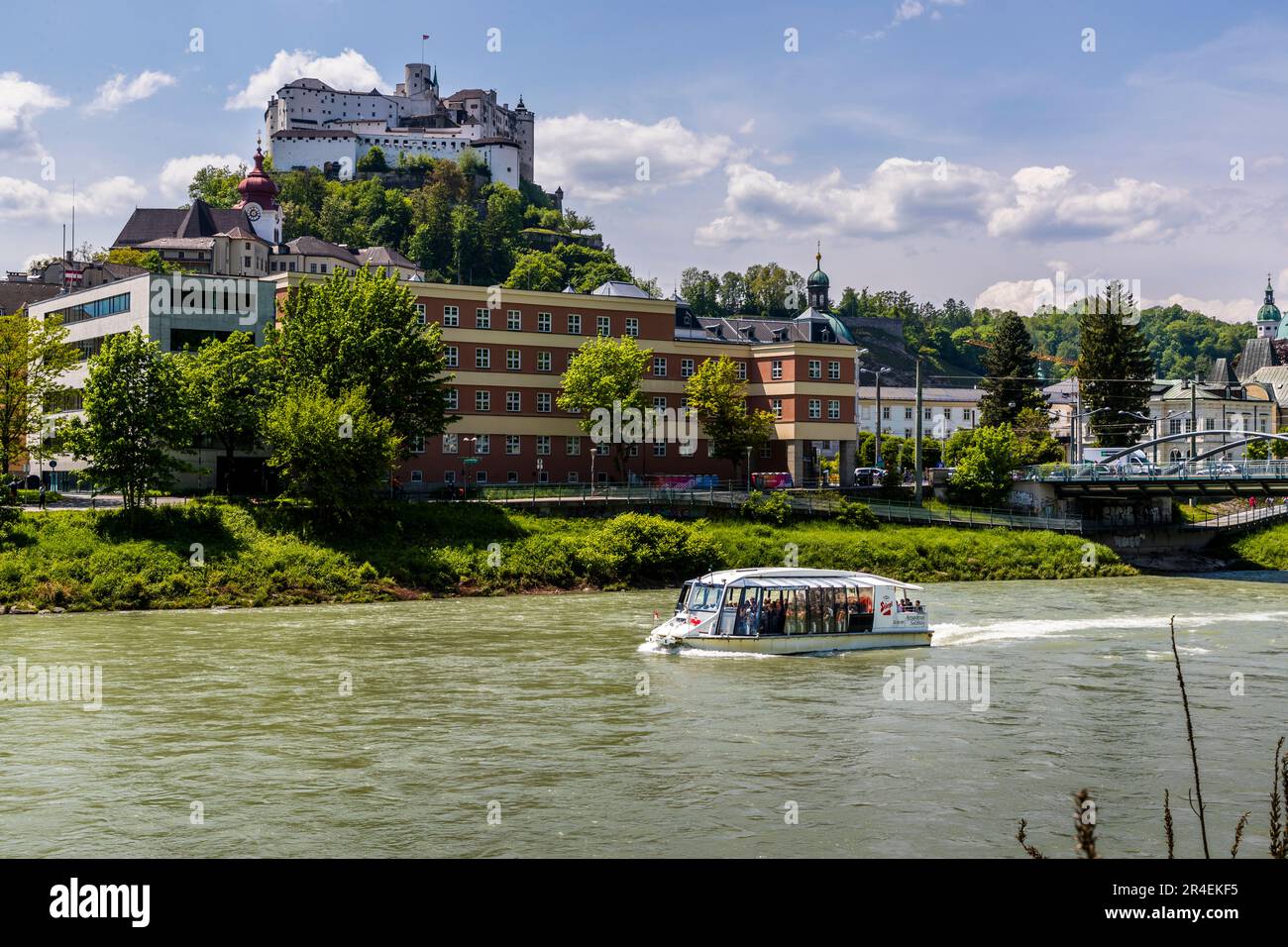 Vista del río Salzach con barco de excursión y fortaleza Hohensalzburg, en el edificio judicial frente y en el puente Nonnentaler derecho en Salzburgo, Austria Foto de stock