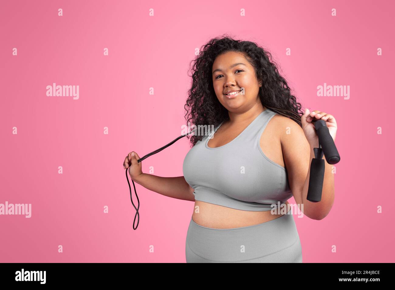 Mujer negra satisfecha más tamaño en ropa deportiva con cuerda para saltar  lista para entrenar sobre fondo rosa, espacio libre Fotografía de stock -  Alamy